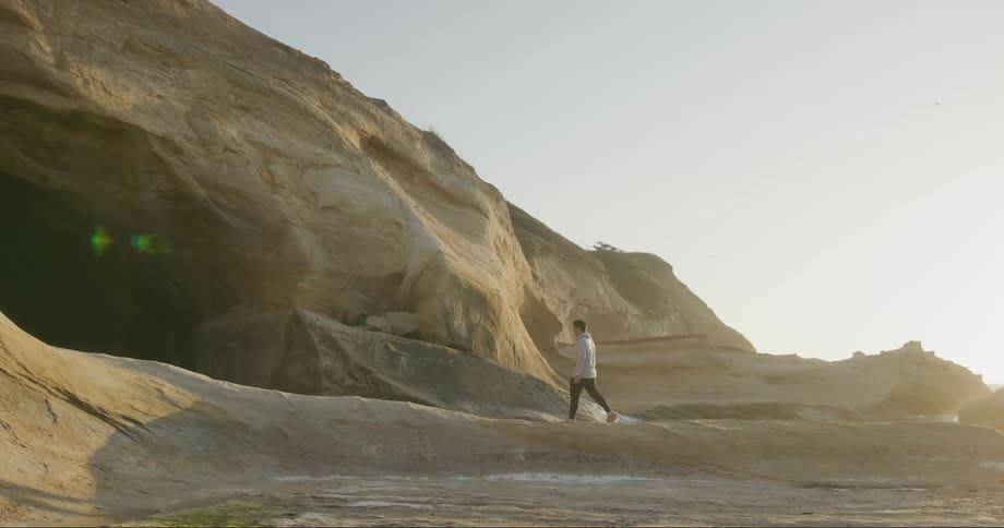 A young man walking into a dark cave