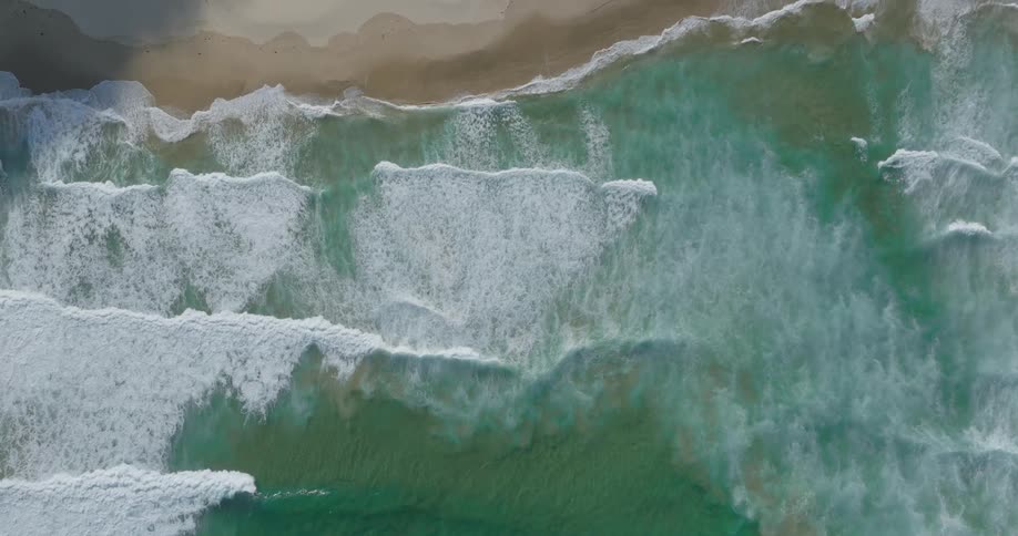 Aerial of a deserted beach with blue water and gentle waves