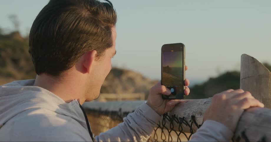 Man using a cellphone to take a photo of the sunrise