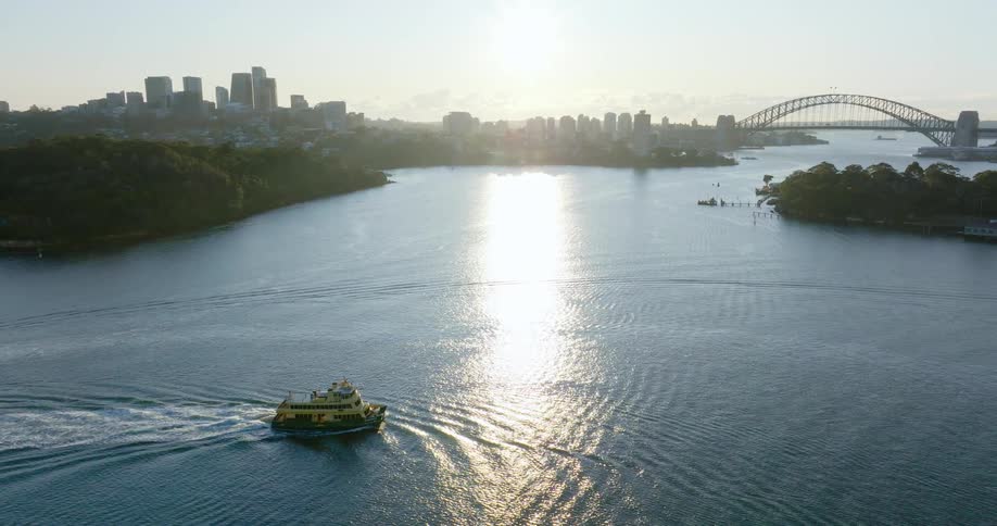 A small boat sailing in a sea near islands and a big city in the background with a huge bridge