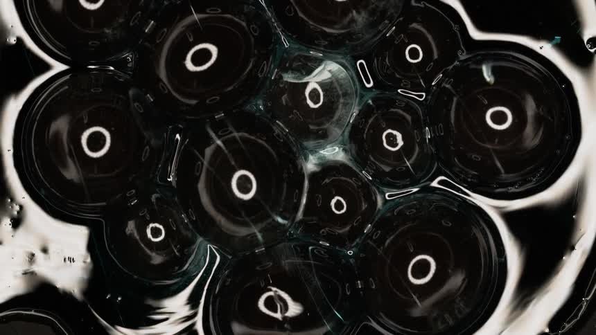 Liquid bubbles on dark background reflect circular light