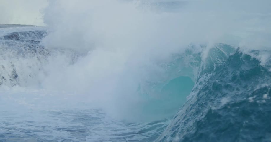 Ocean waves curling and splashing over a rock formation