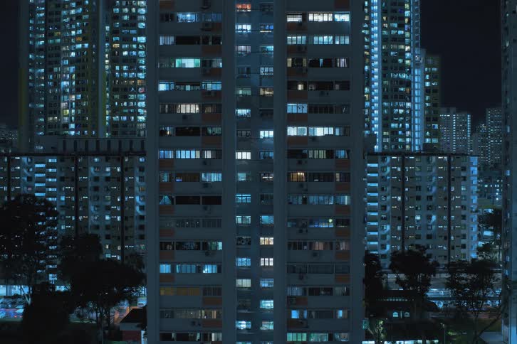 Several tall buildings turn their window lights on at the same time