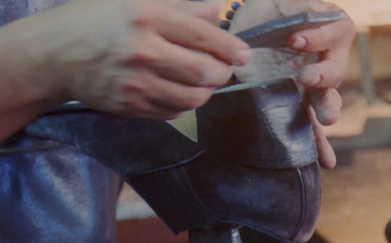 Human hand performing manufacturing work on a leather dress shoe