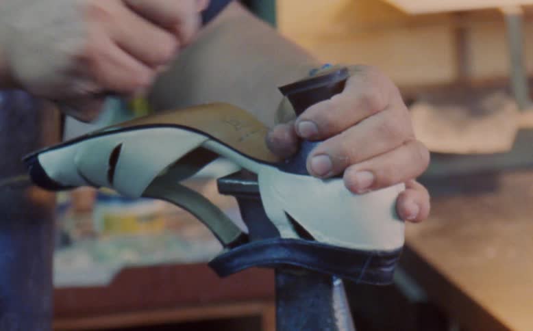 A shoemaker repairs a womans black shoe