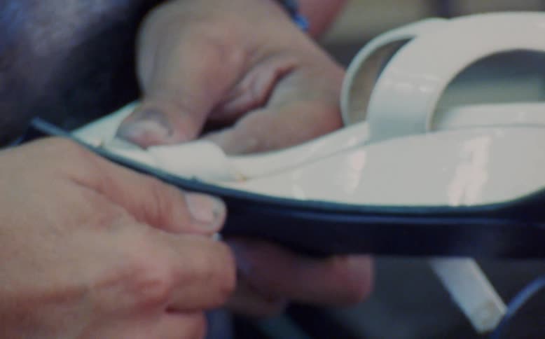Hands hold shoe and cuts sole