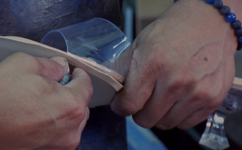 Shoemaker trims extra material from high heeled shoe sole