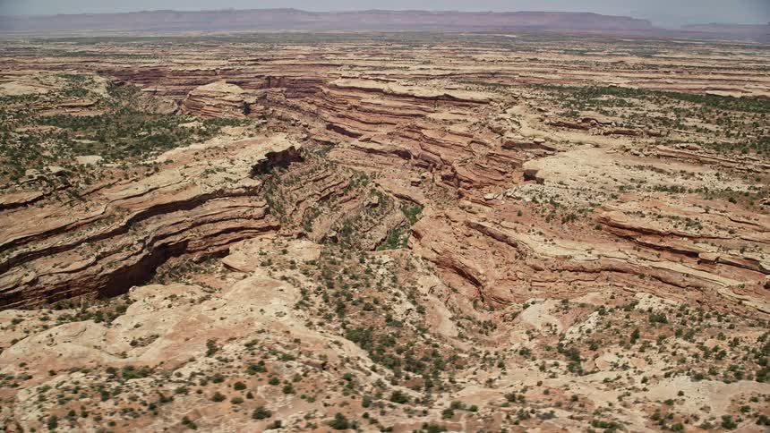 an aerial view of Cedar Mesa in Utah showcasing a stunning canyon passing through a mesa with rock formations cliffs and vibrant vegetation