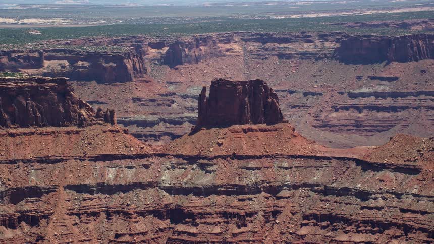 Aerial footage of a desert butte in Canyonlands National Park Utah showcasing tall rock formations and a steep slope