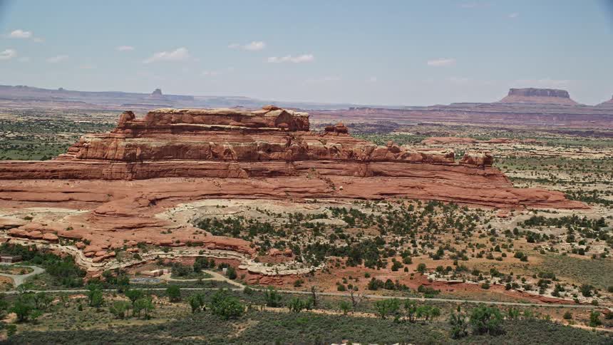 an aerial view of Squaw Butte in Canyonlands National Park Utah showcasing the stunning desert landscape and famous striations with sunshine illuminating the arid hills and wilderness