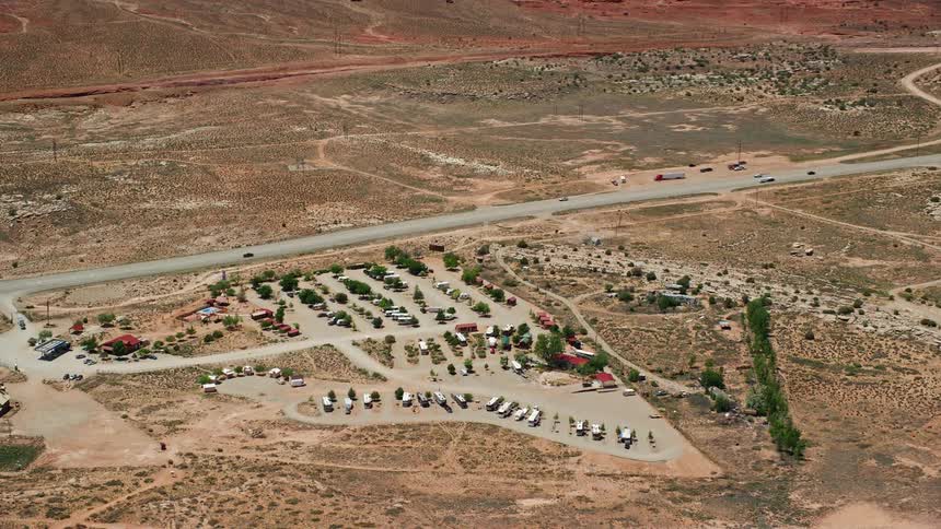Aerial view of traffic passing through arid land with buildings and large parking lots near Archview RV & Resort Campground in Moab Utah