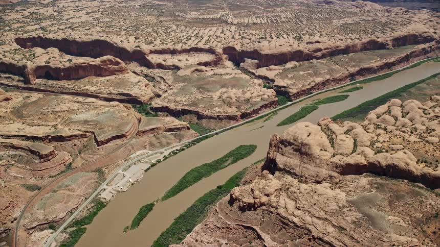 Aerial view of Colorado River and rock formations in Moab Utah with lush green vegetation growing on the river banks