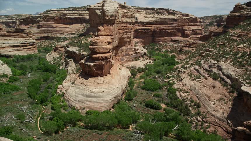 Low altitude aerial footage flying through the arid and sunny Grand Gulch Primitive Area Utah showcasing the breathtaking canyon rock formations and scenic landscape of the Southwest United States