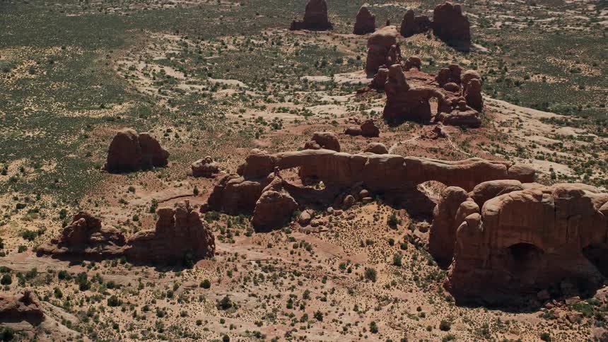 Aerial footage of North Window South Window and Turret Arch rock formations in Arches National Park Utah showcasing the stunning red rocks during a sunny summer day