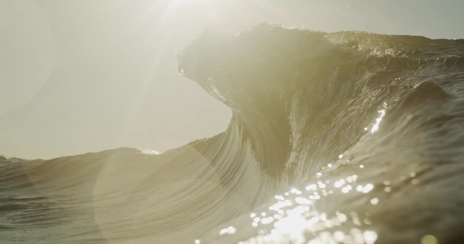 View of a moving ocean wave with reflections of the sun on the water