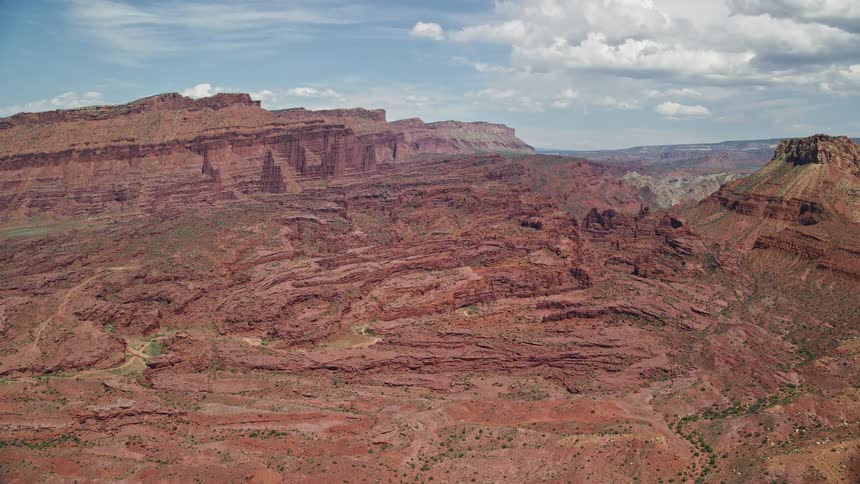 Approaching Fisher Towers at base of mesa capturing the stunning rock formations amidst the arid and sunny Utah landscape