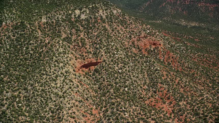 Approaching rocky ledges on a mesa in Manti-La Sal National Forest Utah with green shrubs on the slopes of a mountain