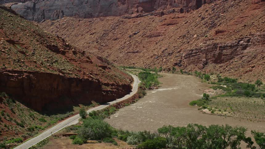 Aerial footage of State Route 128 rapids on the Colorado River and red mountains in Moab Utah during a sunny day in summer