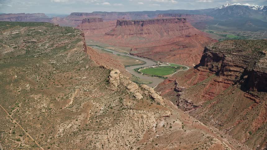  aerial footage captures the stunning Colorado River flowing through a canyon showcasing the beauty of Parriott Mesa and Dry Mesa in Moab Utah during a sunny day in the Southwest United States