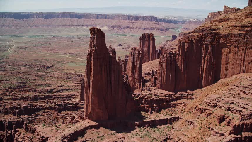 Aerial view of The Titan and other rock formations at Fisher Towers Utah as the camera flies away showcasing the stunning desert landscape