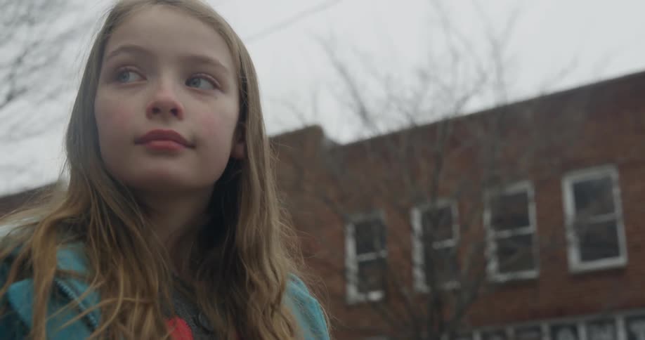 A girl is standing outside on a cloudy day