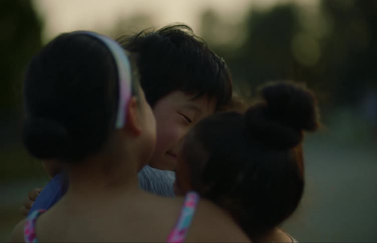 Four children embracing affectionately in an open environment in the late afternoon