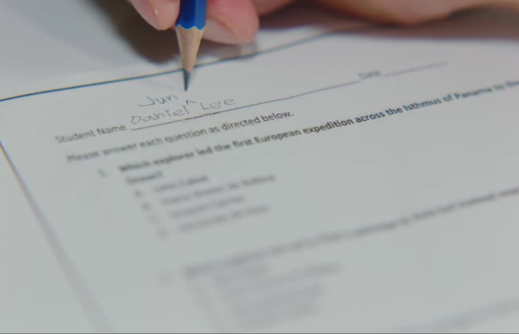Human hand holding a pencil and writing on a paper