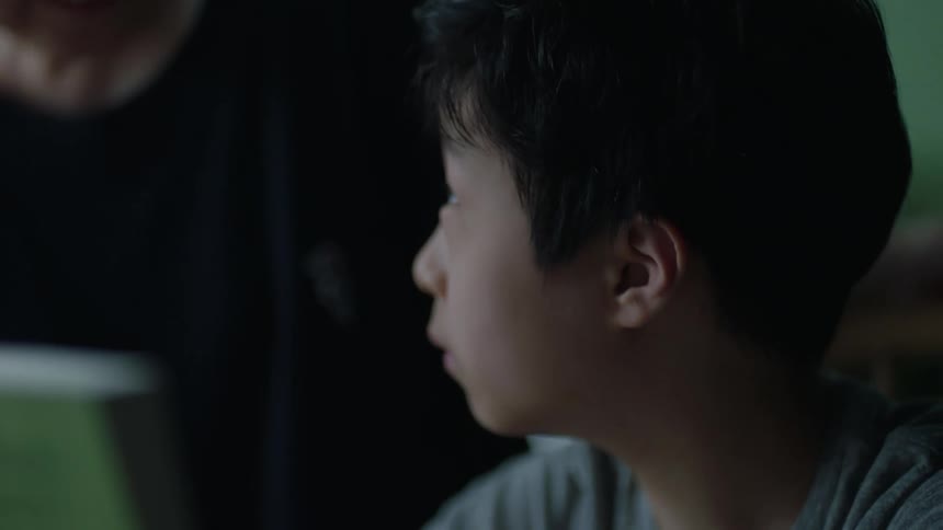 Mother handing a bowl to her son who is sitting on a chair and then he runs his hand through his hair and expresses happiness