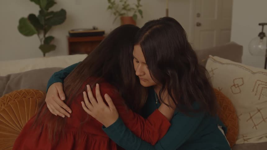 Sad friends hugging on the couch in the living room