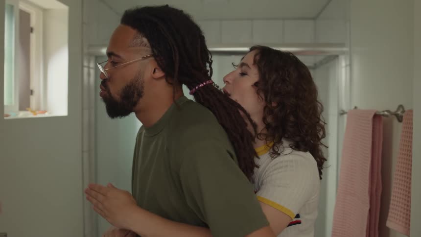 A man and woman are playing around in front of the mirror