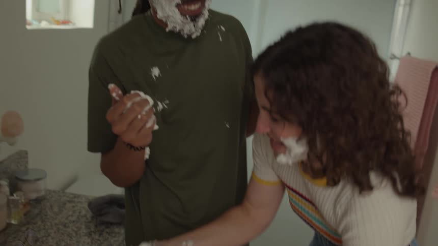 A happy couple is playing with shaving foam in the bathroom