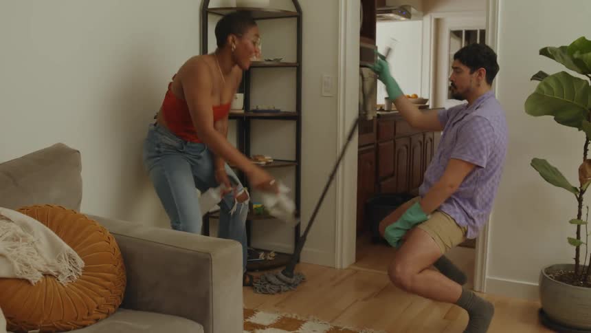 Friends cleaning the house dance together