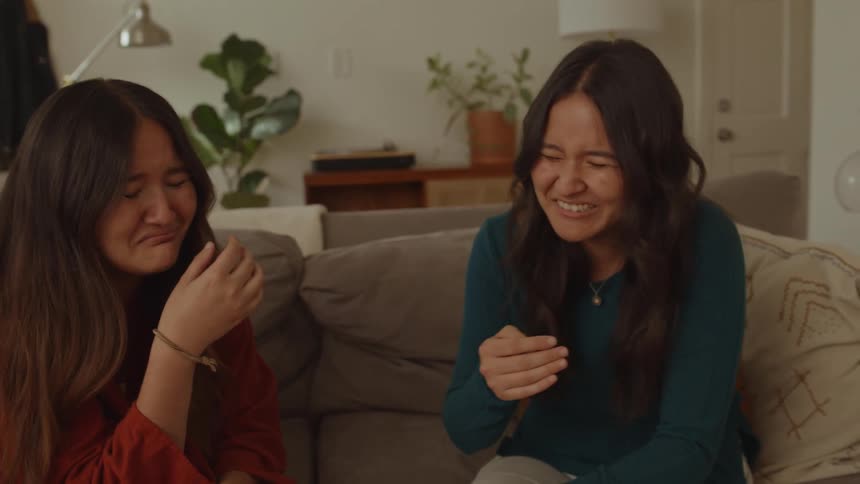 Two friends sitting on the couch talking and laughing a lot