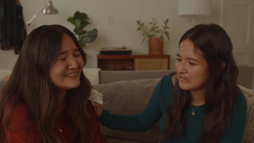 Two women sitting on the couch with one of them crying tears of emotion and happiness