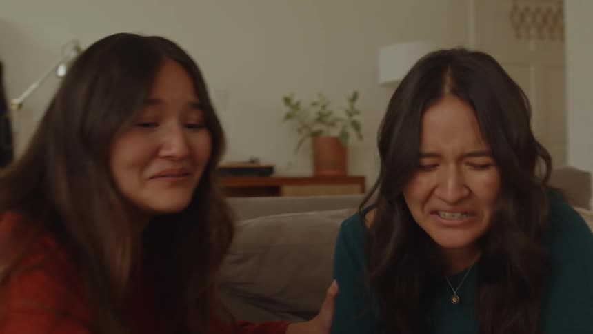 Two teenage girls on a couch laughing so hard theyre crying