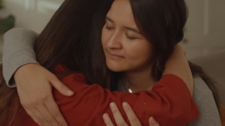 Two friends sitting on the couch hugging each other