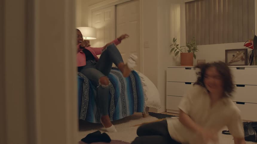 Woman helps a friend to take her boots off on the bedroom
