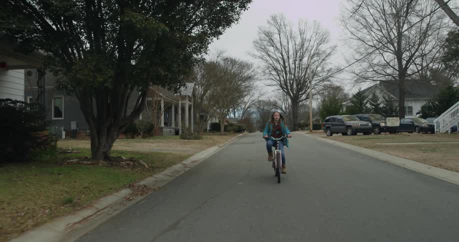 A girl rides out onto the street on a bike