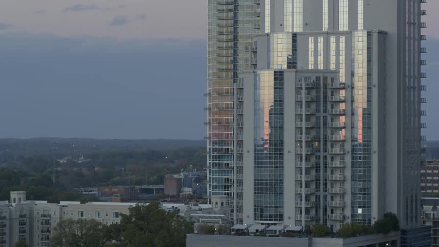 A tall building is reflecting a sunset ahead