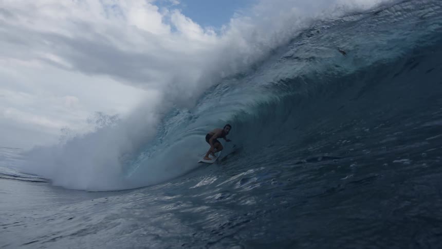 A man in shorts is surfing in the sea as the waves goes by