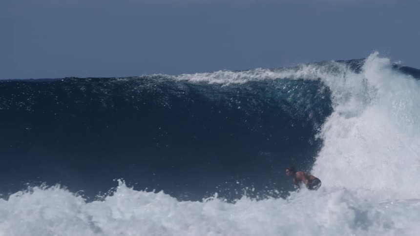 Men are surfing on a large wave