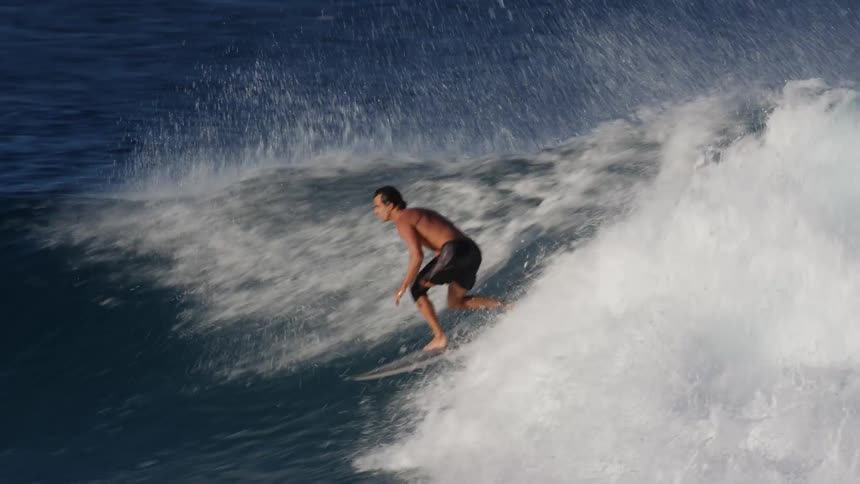 Surfer rides surfboard along cresting wave