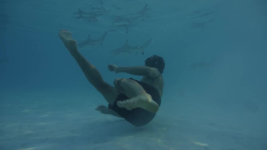 A young man swimming with sharks and rays
