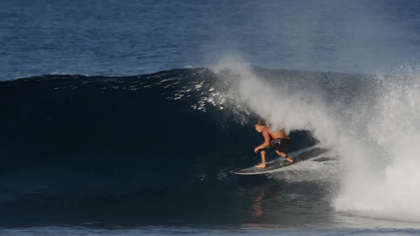 Man rides a wave with a surfboard in the ocean at daytime