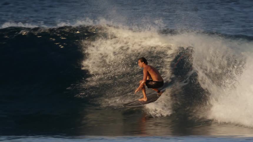Man maneuvering his surfboard and riding a small wave