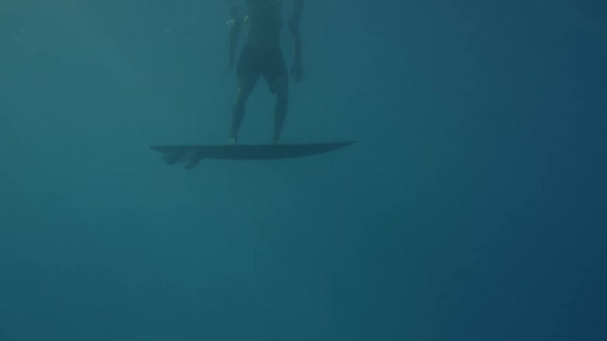 Man stands on a surfboard submerged in the ocean