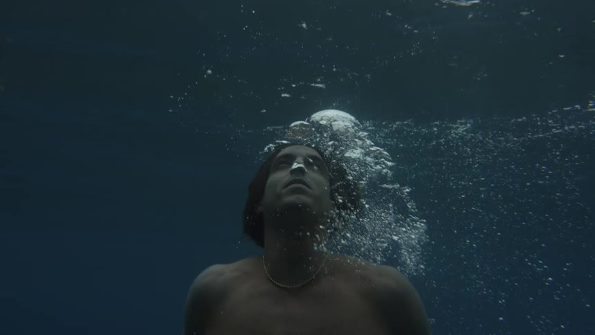 Swimmer blows out bubbles while rising toward the surface