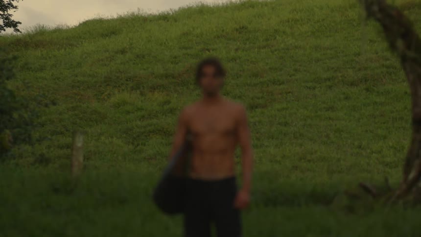 Man holding his surfboard with one of his arms in a natural environment