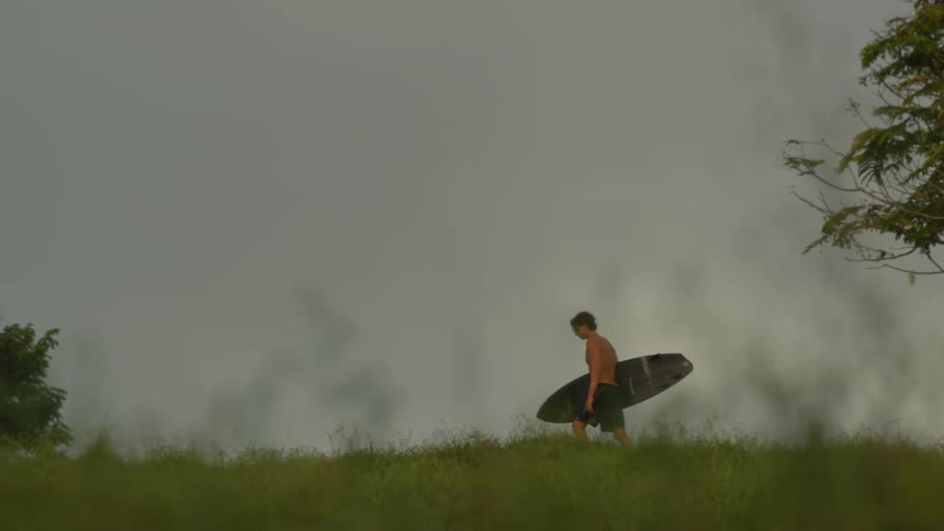 A man is carrying a surfboard on the field