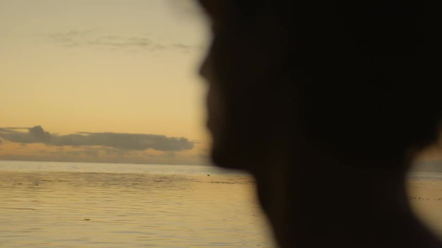 A person in silhouette looks at the sea